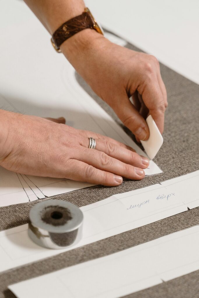 Close-up of a tailor marking fabric patterns with precision tools in a workshop.